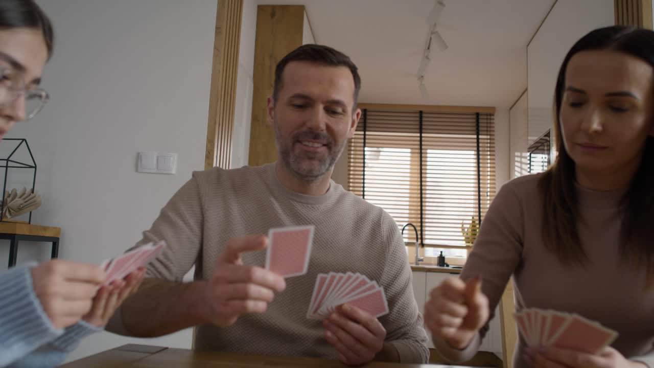 zoom en de familia caucásica de padres y adolescente jugando a las cartas por la mesa