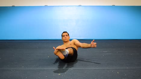 un tipo haciendo una sujeción estática en un gimnasio de gimnasia ejercitando sus abdominales y músculos centrales todavía disparados