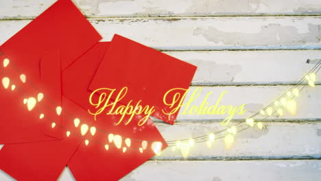 animation of happy holidays text over red envelopes on wooden background