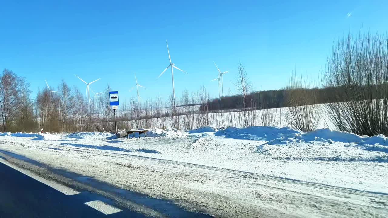 Winter Landscape with Wind Turbines in a Snow Covered Field under Blue Sky