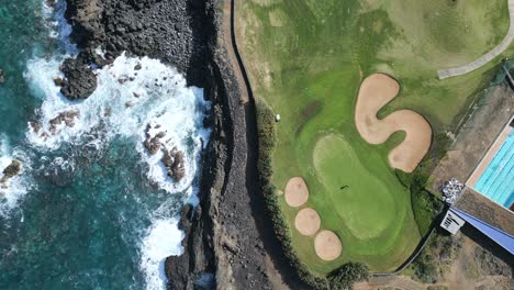 golfer walks on green as ocean waves crash below epic seaside course