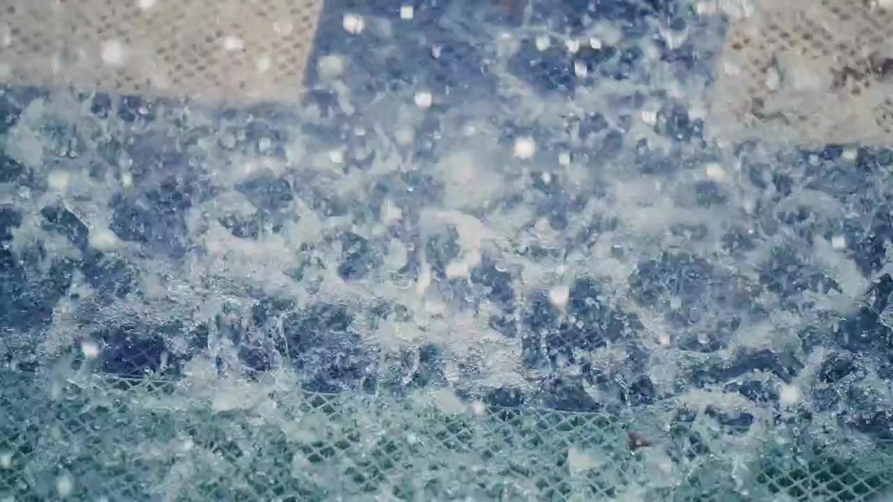 Close-up of Water Splashing on a Mesh Surface