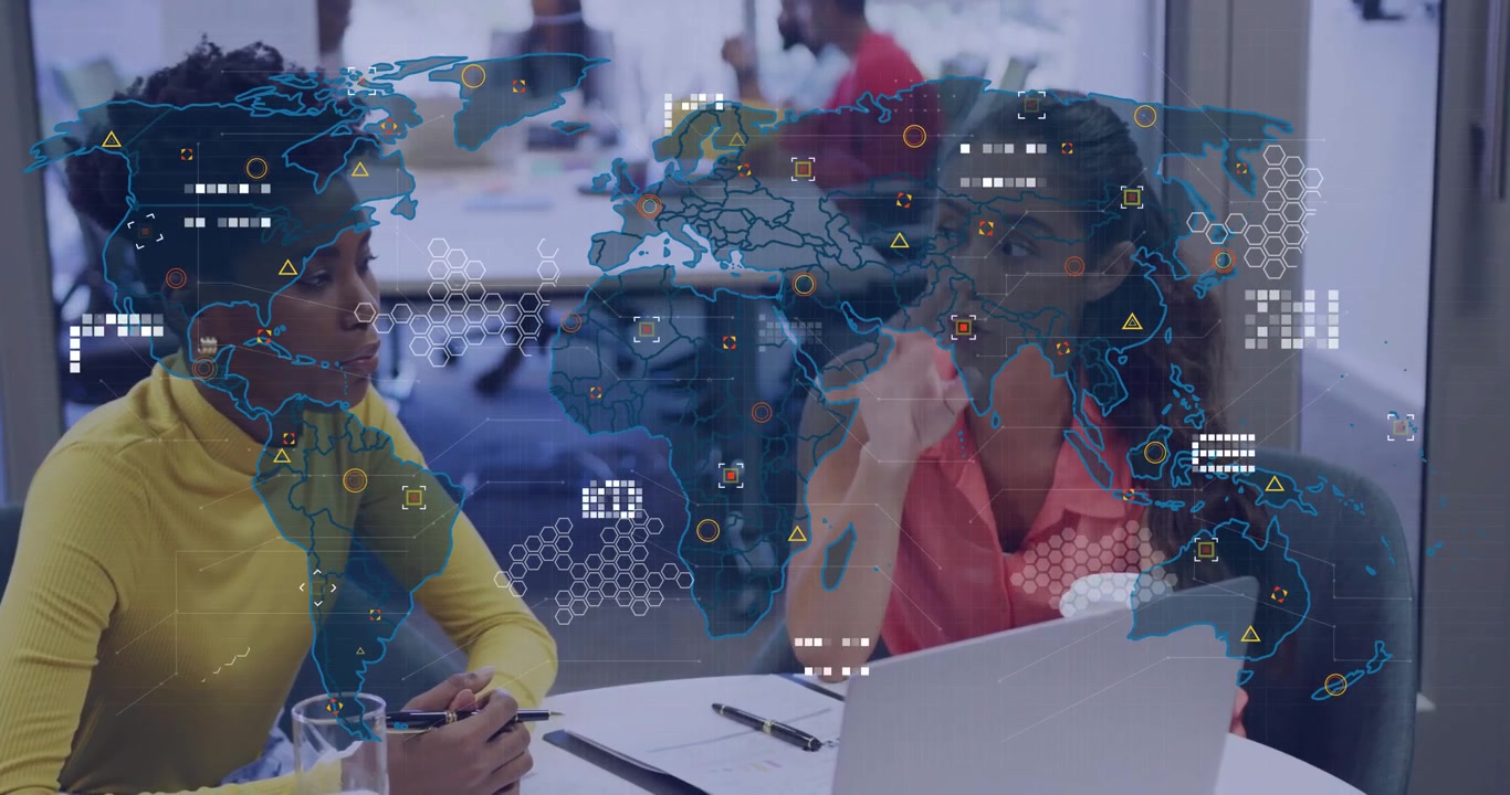Two female coworkers discussing data visualization in tech office, with digital world map overlays