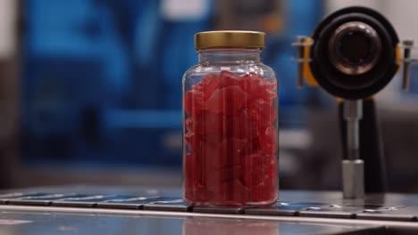 red multivitamin supplement gummies in clear bottles on conveyor belt