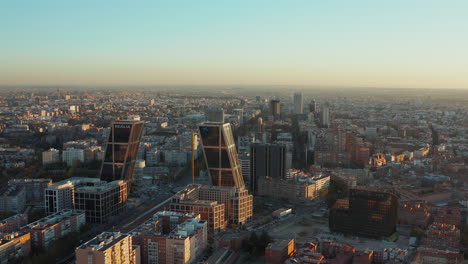 Forwards-fly-above-business-district-of-city-in-evening-sunlight.--Leaned-office-twin-towers-at-Plaza-de-Castilla-square.