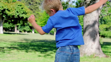 boy jumps around and spinning with his arms spread before stopping and looking at the camera