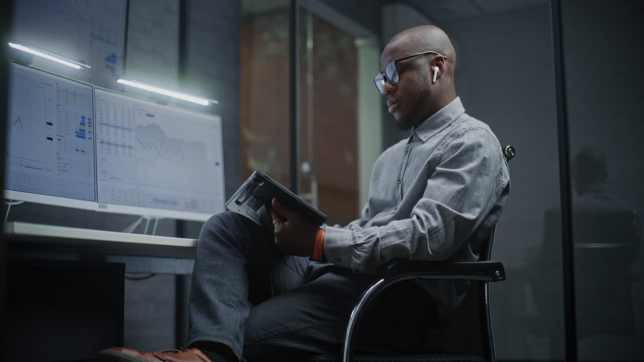 Financial Analyst Working on Computer with Multi-Monitor Workstation, Analyzing Real-Time Stocks and Market Charts, Talking on Phone. African American Businessman Works in Office. Vertical Shot.