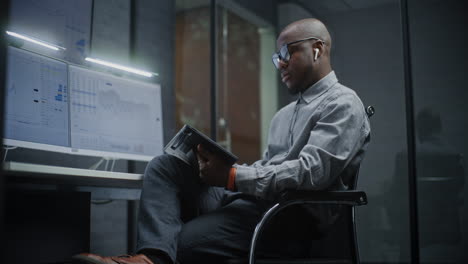 financial analyst working on computer with multi-monitor workstation, analyzing real-time stocks and market charts, talking on phone. african american businessman works in office. vertical shot.