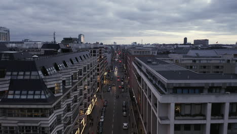 Evening-city-from-rooftop-level.-Forwards-fly-above-busy-street-in-urban-borough-at-dusk.-Berlin,-Germany