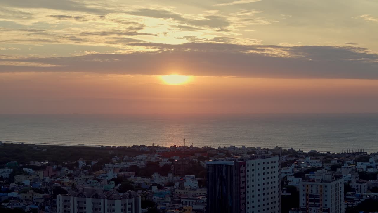Aerial shot capturing sunn getting covered by thick clouds at horizon with cityscape in foreground.