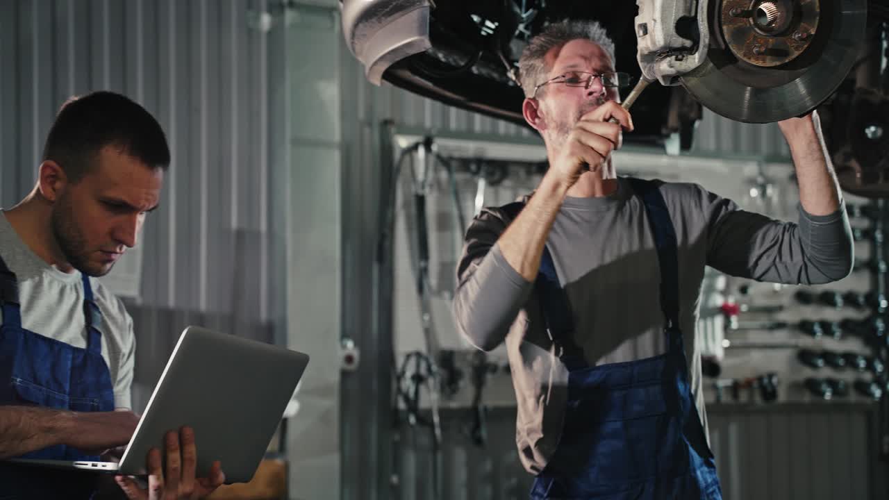 Two mechanics repairing a car's brake system