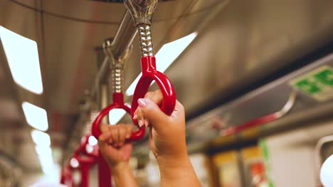 manos agarrando manijas en un tren en movimiento