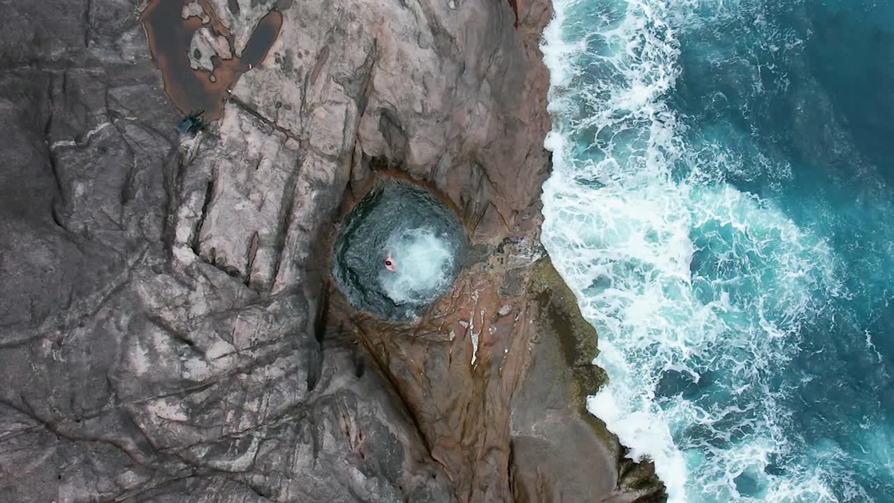 A man jumps into a rock pool