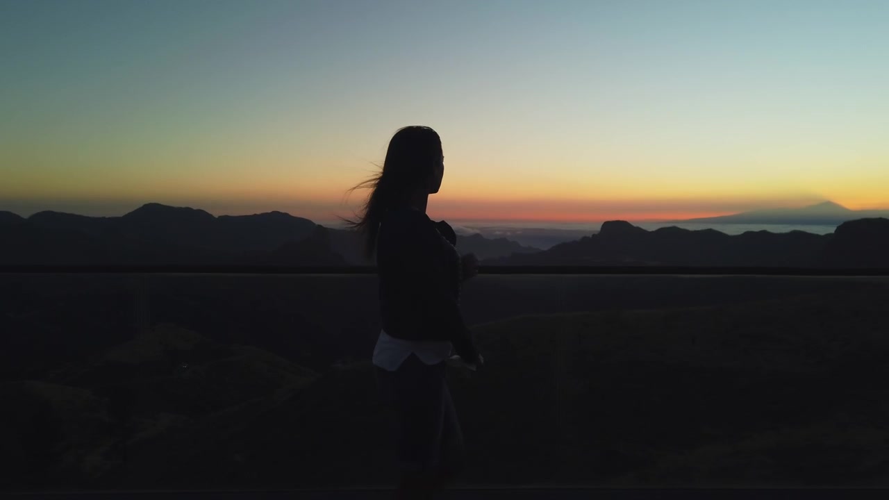Silhouette femminile che si gode la splendida vista sulle montagne da un punto panoramico a Tejeda, Gran Canaria. Sera tranquilla con un cielo bellissimo