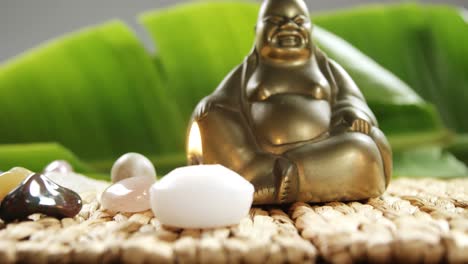 Close-up-of-laughing-Buddha-figurine-with-pebble-stone