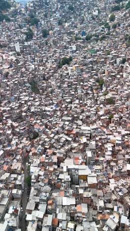vertical: drone pans over rio de janeiro's favela rocinha showing christ redeemer in background
