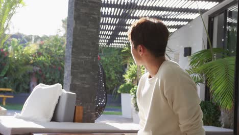 happy asian male teenager sitting and relaxing on sunny day in garden