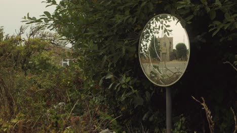 Cyclist-rides-in-the-reflection-of-traffic-mirror-on-the-road-in-a-Wide-Shot