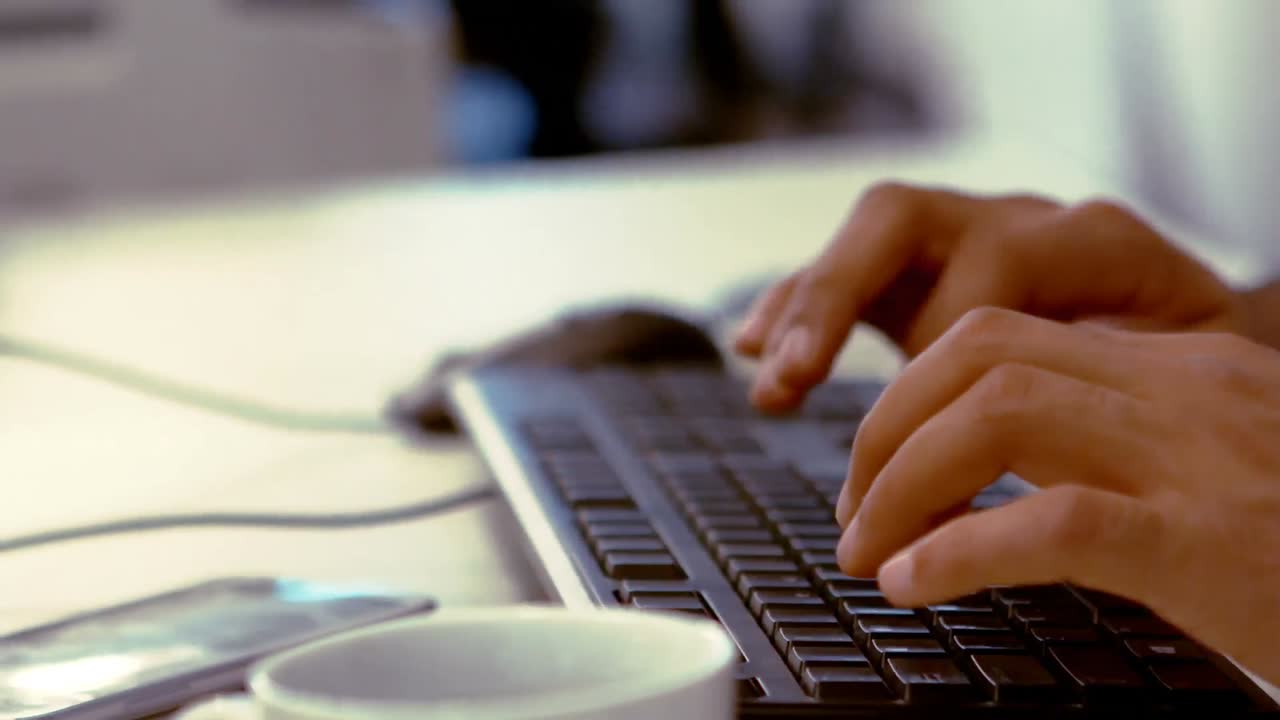 Hånden til en forretningsleder som skriver på tastaturet ved skrivebordet