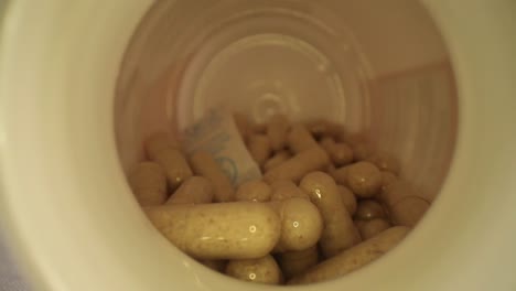 moviéndose más allá de la tapa de la botella, en toda la longitud de una botella de píldora suplementaria con desecante todavía en