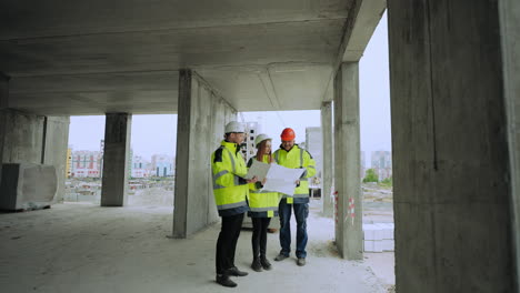 engineers and building inspectors are examining building plan in laptop in construction site