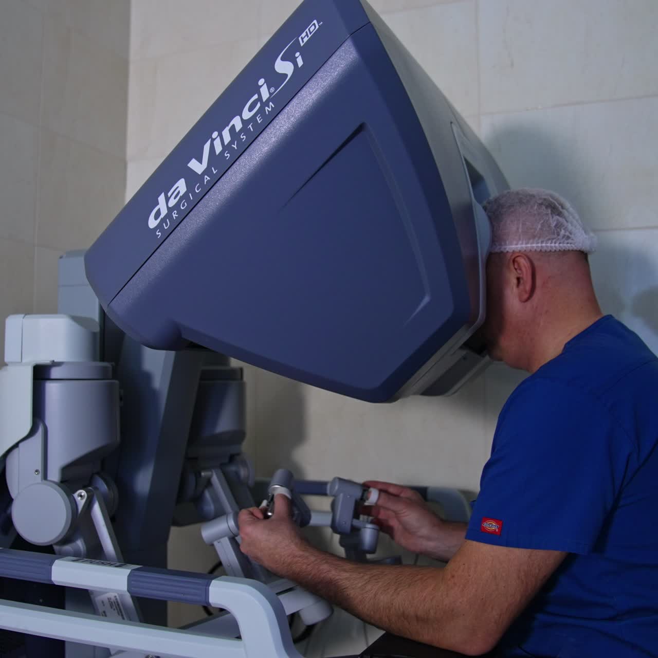 Male main surgeon sitting at the control unit of surgeon robot. Doctor operating the patient managing the master control console
