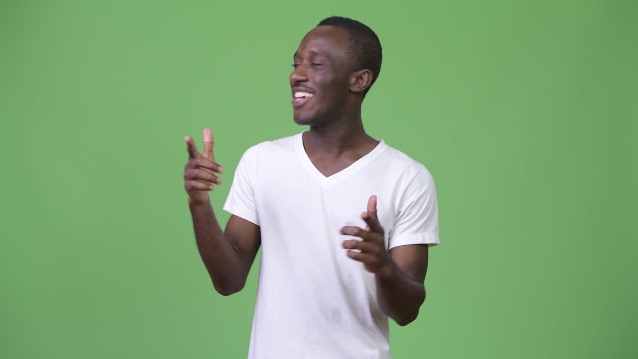 Young happy African man talking against green background