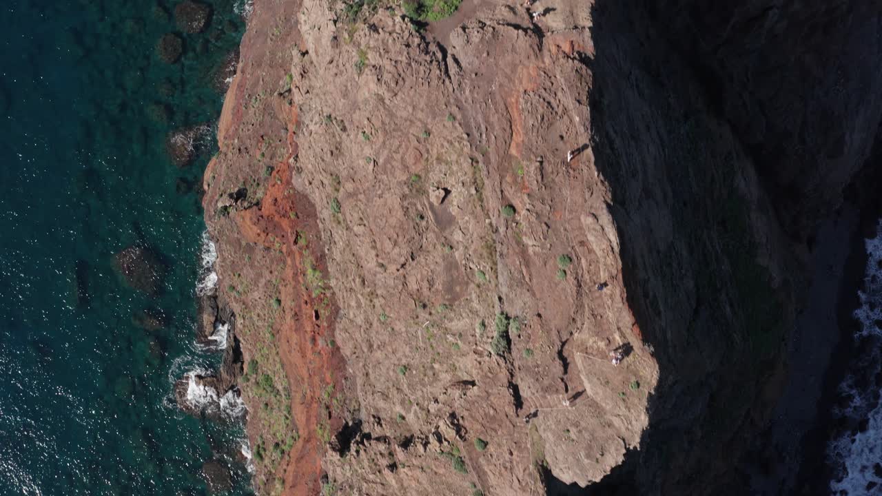 personas caminando en una cordillera delgada con el océano a cada lado durante un día soleado