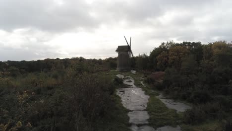 Traditional-wooden-stone-flour-mill-windmill-preserved-in-Autumn-woodland-aerial-view-countryside-rising-up