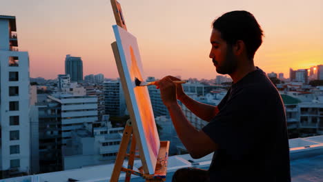 artist painting on rooftop at sunset