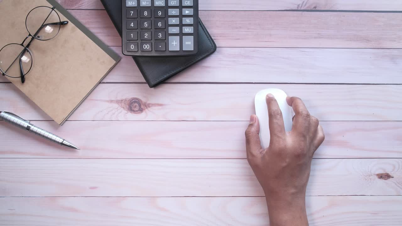 persona que trabaja en un escritorio con una calculadora, un ratón y un cuaderno.