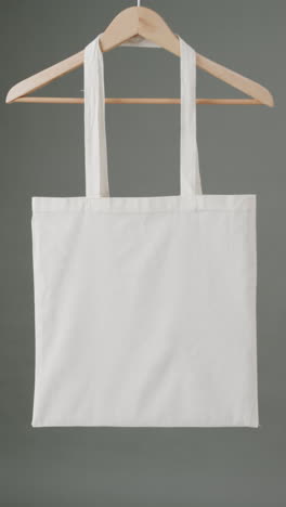 vertical video of hanger with white canvas bag and copy space on grey background