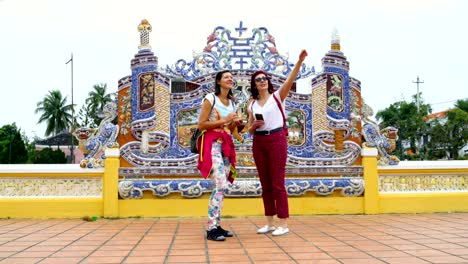 women with smartphones are standing next to a buddhist temple