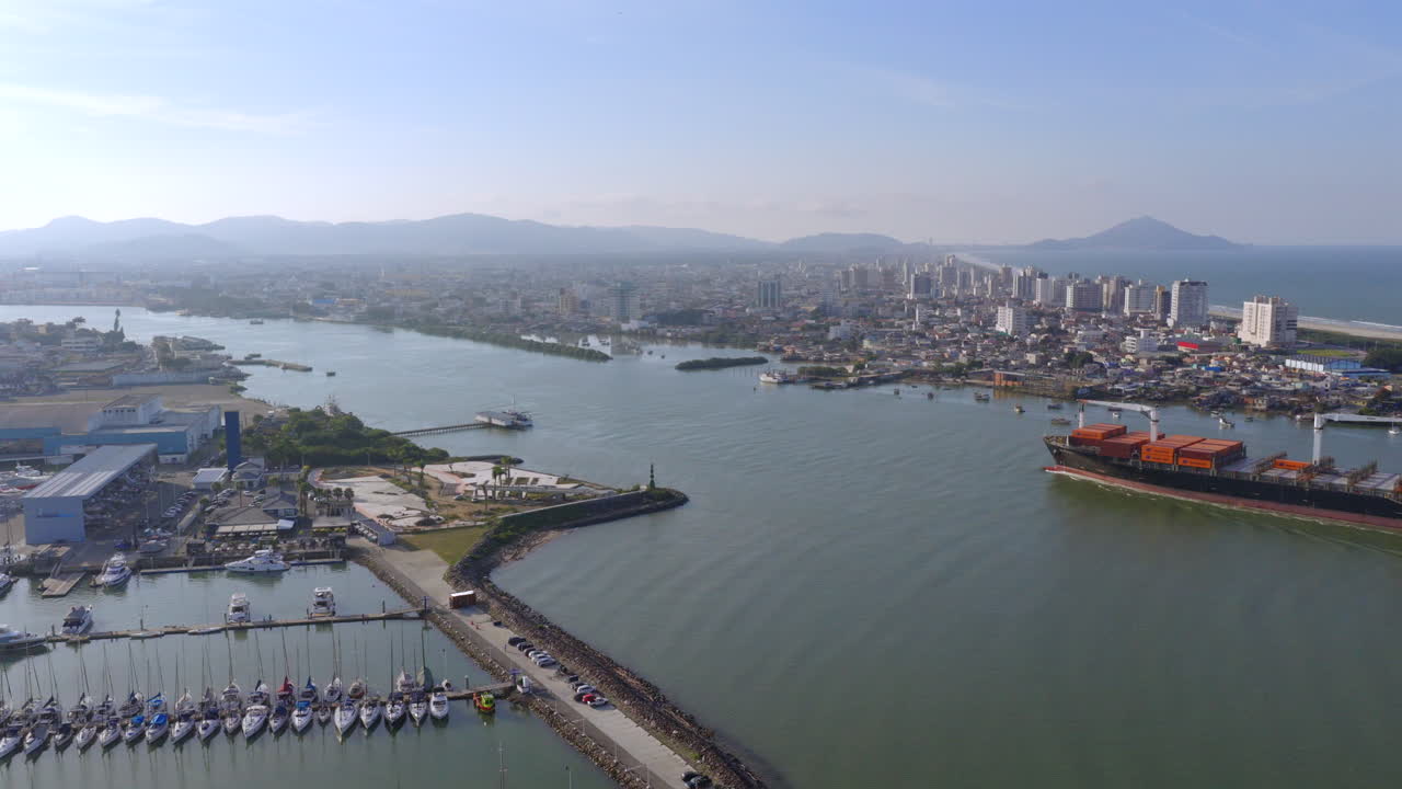 Panoramic aerial fly at Itajaí port with cargo ship and Itajaí city skyline, Santa Catarina, Brazil