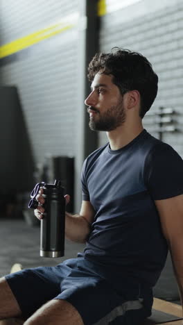 man drinking water after workout in gym