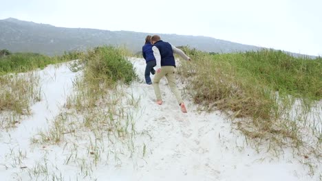 hermanos persiguiéndose unos a otros en las dunas de arena