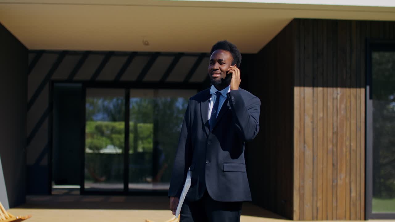 Businessman talking on phone outside modern home