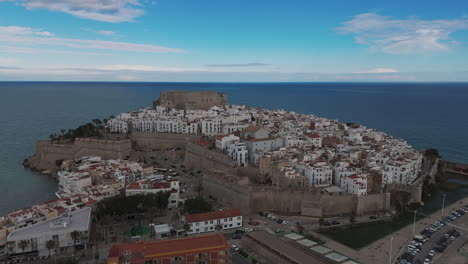 drone circles historic peniscola castle surrounded by sea with visible coastal cliff