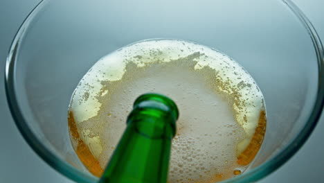 bottle pouring craft beer in transparent glass closeup. ipa jet making bubbles