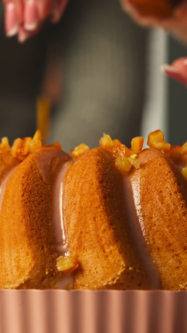 Close-up of candied fruit being sprinkled over a glazed Easter bundt cake, vertical