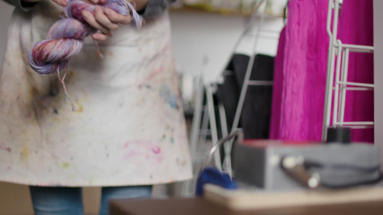 amplio ángulo bajo de mujer en la tienda de casa poniendo hilo en un rodillo de madeja mecánico y enrollándolo