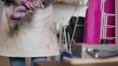 wide low angle of woman in home shop putting yarn on a mechanical skein roller and rolling it