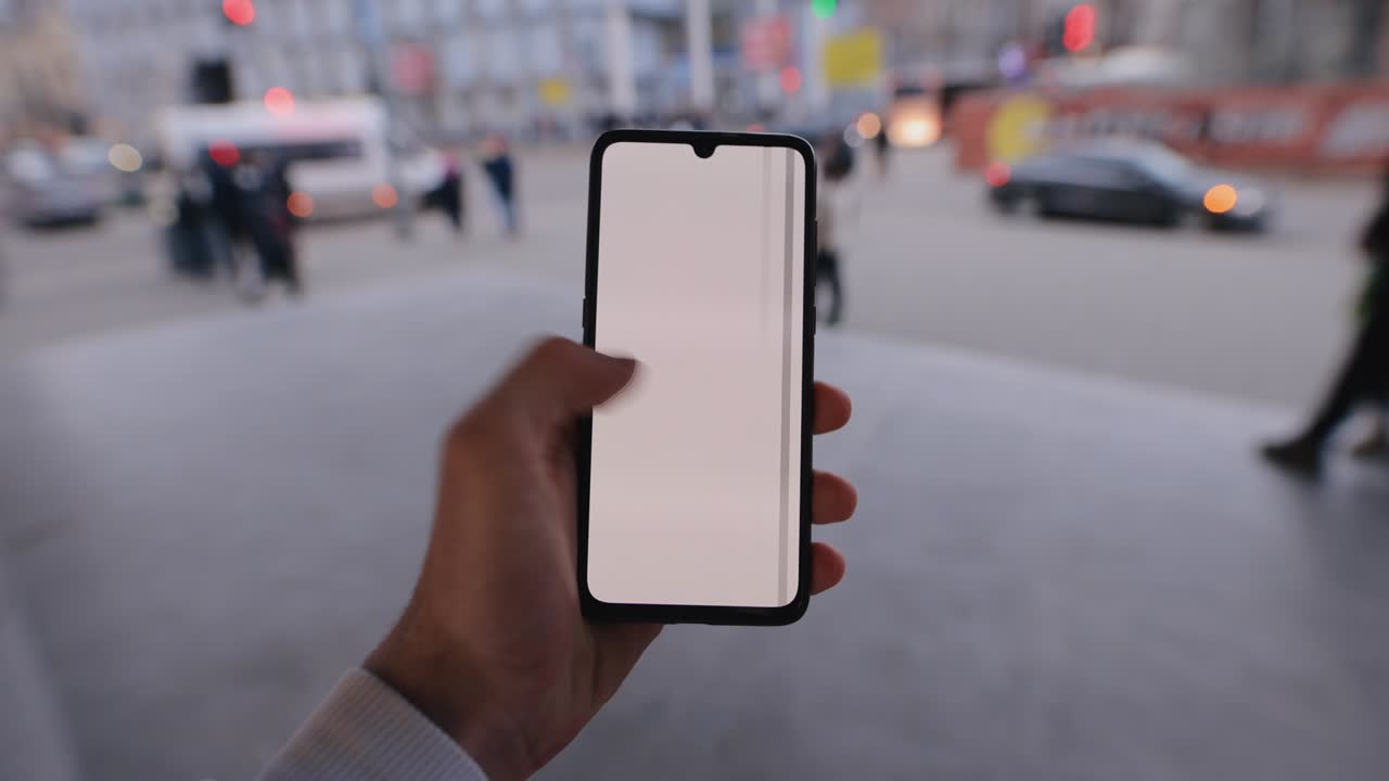 hombre con la mano sosteniendo una maqueta de teléfono inteligente en una ciudad desliza a la izquierda la pantalla táctil
