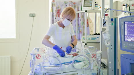 nurse caring for newborn in incubator