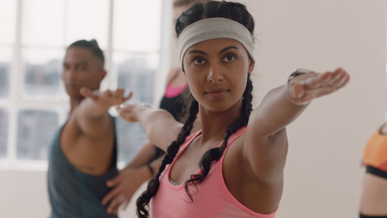hermosa joven mujer de raza mixta haciendo ejercicio en clase de yoga practicando pose de guerrero disfrutando del entrenamiento físico en grupo