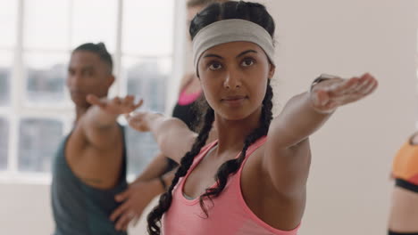 beautiful young mixed race woman exercising in yoga class practicing warrior pose enjoying group physical fitness workout