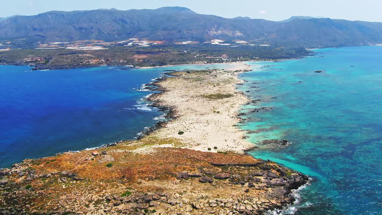 Aerial: Rising landscape shot of famous Elafonissi beach and shallow Balos lagoon with azure blue water, Crete Island, Greece