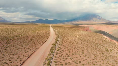 Desert-dirt-road-near-a-cliff-and-volcanoes