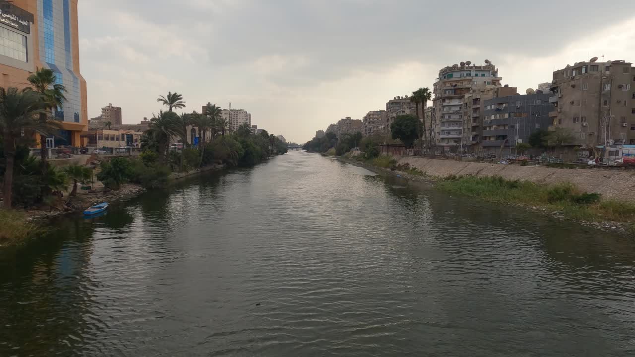 vía fluvial en la ciudad de el cairo con edificios antiguos y palmeras en un día nublado en egipto