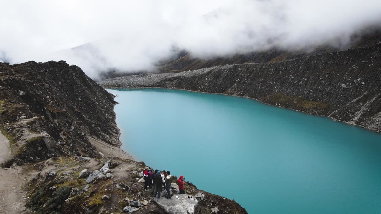 tiro de drone de amigos en un lago turquesa nublado en las tierras altas y montañas de huaraz peru